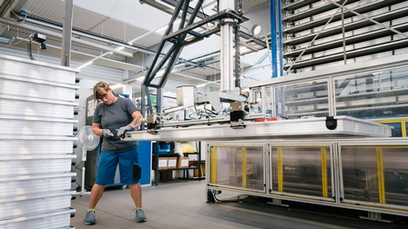 Person steht in Industriestätte und bearbeitet Solarpaneel