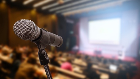 Nahaufnahme eines Mikrofons vor einem Publikum in der Unschärfe