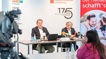 Peter Voithofer und Gerhard Wohlmuth sitzen hinter einer Tisch und sprechen zu den Journalisten bei der Pressekonferenz zur Halbjahresbilanz