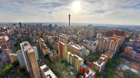 Stadtansicht von Johannesburg: Blick von oben auf zahlreiche bunte Wolkenkratzer, darunter der Hillbrow Tower in der Hauptstadt von Südafrika.