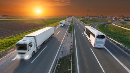 Ein Lkw und ein Bus auf einer Straße in Bewegungsunschärfe im Sonnenuntergang.