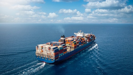 Ein Frachtschiff mit vielen Containerstapeln auf dem offenen Meer
