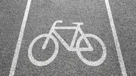 Detailansicht Asphaltstraße mit weißem aufgemalten Fahrradzeichen