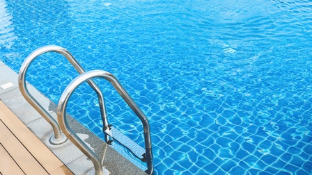 Eine metallene Leiter führt in ein großes Becken, das mit klarem Wasser befüllt ist