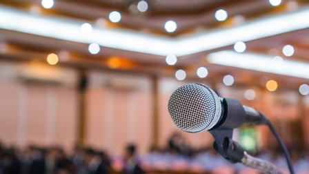 Nahaufnahme eines Mikrofons vor einem Publikum in der Unschärfe