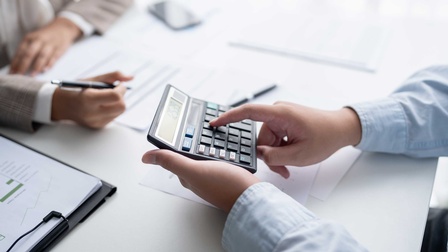 Eine Person tippt auf einem Taschenrechner