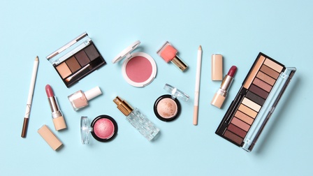 Make-up Kassetten, Nagellacke, Lippenstifte und Rouge Dosen auf einem hellblauen Untergrund, Vogelperspektive