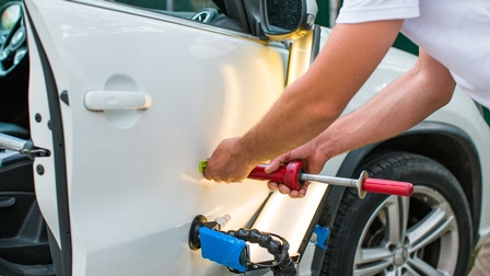 Ein Dellentechniker beim Ausbeulen einer Blechdelle