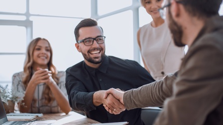 Handschlag im Büro mit Businesspartnerinnen und fröhlicher Stimmung