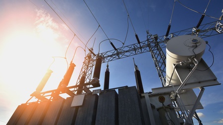 Ansicht Speicher eines Stromkraftwerkes nach oben mit Stromleitungen verbunden unter blauem Himmel mit Sonnenlicht
