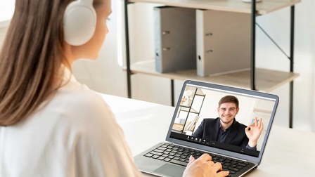 Eine Person sitzt vor einem Laptop und führt einen Video-Call