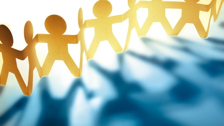 Konzept Teamwork mit einer Papierkette aus Personen, die sich an den Händen halten