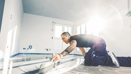 Person am Boden kniend beim Verstreichen von Zementmörtel