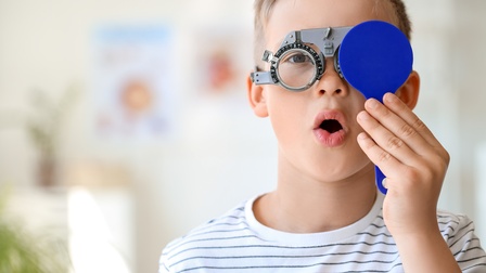 Kind trägt eine professionelle optometrische Brille und führt einen Sehtest durch