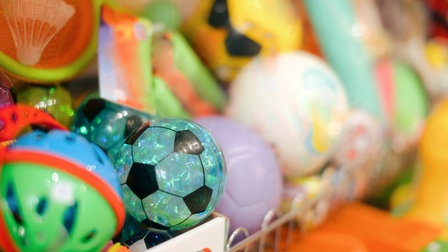 Nahaufnahme vieler verschiedener Bälle in unterschiedlichen Größen und Farben in einem Regal