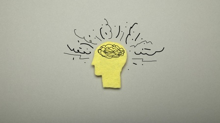 Grafische Darstellung gelber Kopf in Seitenansicht mit Gehirn und Linien, die Kopf umgeben