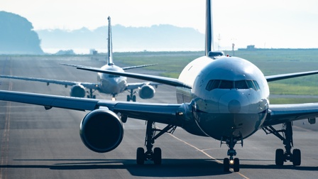 Zwei hintereinander rollende Flugzeuge in Frontalansicht auf Landebahn