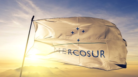 Weiße Fahne mit Mercosur Schrift und Sternen weht bei Abenddämmerung