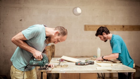 Personen verarbeiten Holz in einer Werkstatt 