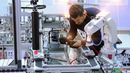 Industrie 4.0, Person arbeitet mit Roboterarm in einer Produktionsstätte