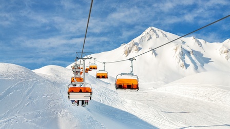 Ein Sessellift fährt einen verschneiten Berghang hinauf