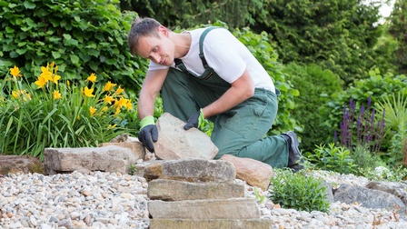 Ein Gärtner beim anlegen einer Steintreppe in einem Garten