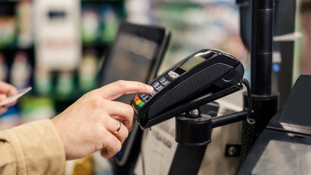 Nahaufnahme von einem Bezahlvorgang mit Händen, die mit Karte an einem EC-Terminal bezahlen