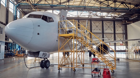 Kleines Flugzeug in Hangar stehend, seitlich gelbe Metalltreppe an offener Tür des Flugzeugs 