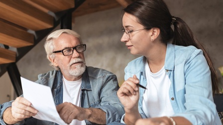 Älterer Mann erklärt junger Frau anhand eines Dokumentes Betrieb