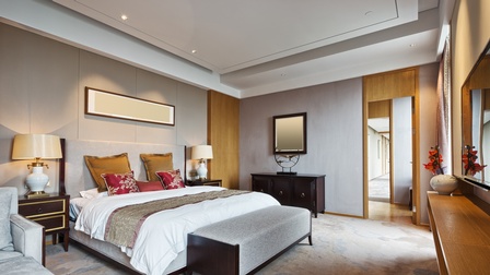 Ansicht eines modernen Hotelzimmers in grauen Tönen sowie Eichenholz-Elementen mit indirekter Beleuchtung