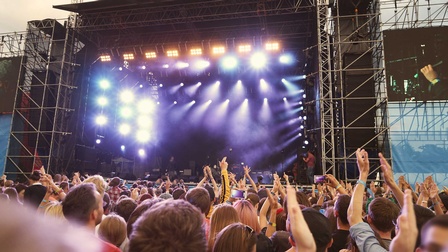 Eine Menschenmenge für einer Konzertbühne bei einem Open Air Musikfestival