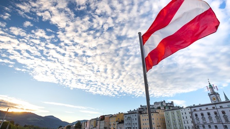Österreichflagge weht im Wind vor einer Stadtkulisse in Salzburg