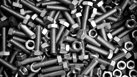 Nahaufnahme sehr vieler länglicher, dunkelgrauer Schrauben, an deren einem Ende eine Mutter jeweils steckt