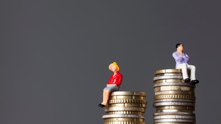 Zwei Figuren sitzen auf unterschiedlich hohen Münzstapeln.