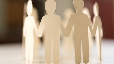 Girlande aus hellem Papier ausgeschnittene Personen, die als kleine Papierfiguren einen geschlossenen Kreis und halten sich dabei an den Händen halten