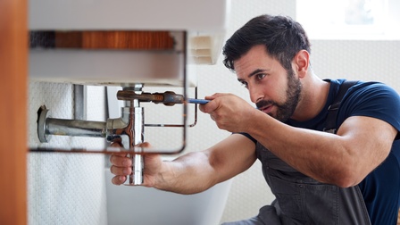 Installateur schraubt an Waschbecken in einem Badezimmer