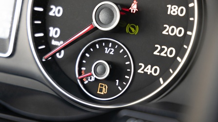 Detailansicht eines Cockpits in einem Auto mit rot leuchtenden Warnanzeigen für den Tankstand sowie für das Anschnallen