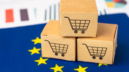 Kleine Pakete mit aufgedruckten Symbolen von Einkaufswägen, platziert auf blauem Untergrund mit gelben Sternen