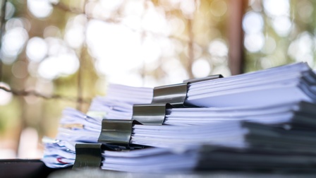 Detailansicht eines Aktenstapels mit schwarzen Klammern 