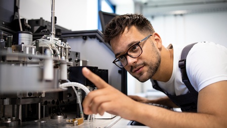 Person mit Brillen inspiziert Maschine