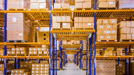 Große Lagerhalle mit gelbblauen Regalen voller Kartonagenboxen