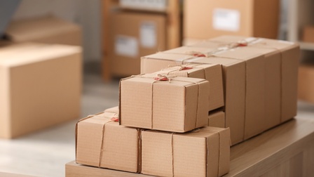 Kartonagen Pakete verpackt und bereit für den Versand stehen auf einem Regal während im Hintergrund weitere Pakete stehen