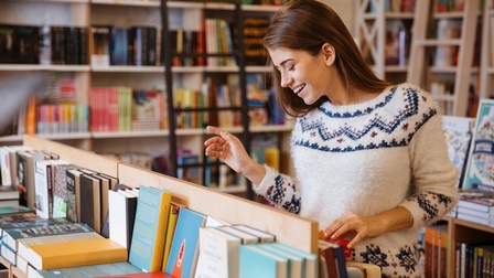 Junge Frau stöbert in einer Buchhandlung