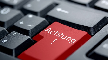 Rote Taste einer Tastatur mit Aufschrift Achtung in weißem Schriftzug