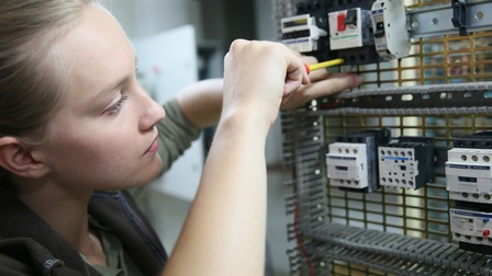 Detailansicht einer Person, die in elektronischen Verteilerkasten schraubt