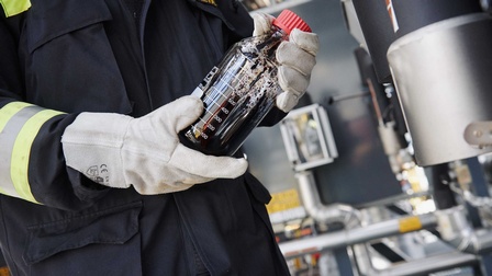 Eine Person hält eine Flasche mit Rohöl in den Händen