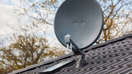 Eine Satellitenschüssel auf dem schrägen Dach eines Hauses