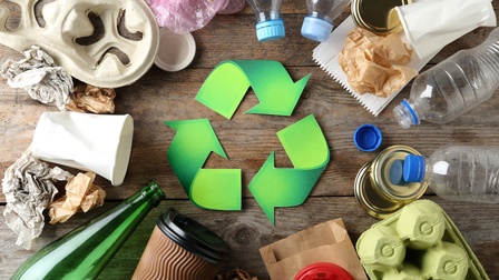 Recycling Konzept mit Recycling Symbol und unterschiedlichen Materialien auf einem Holzuntergrund, Topview