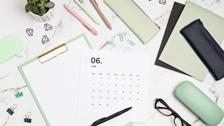 Notizblöcke, Kalenderblatt, Stifte, Brille und Etui, Büroutensilien und kleine grüne Pflanze liegen auf Marmoruntergrund, Topview, Flatlay