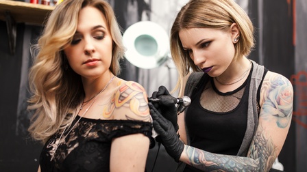 Person tätowiert die Schulter einer anderen Person in einem Tattoo Studio